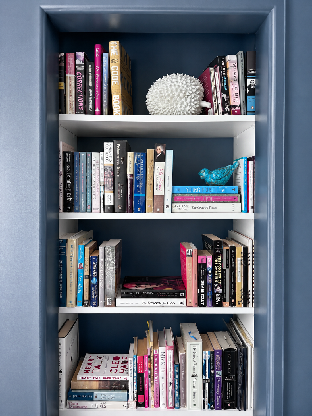 Built-in bookcase architectural detail with painted blue surround and white shelving styled with books and decorative objects