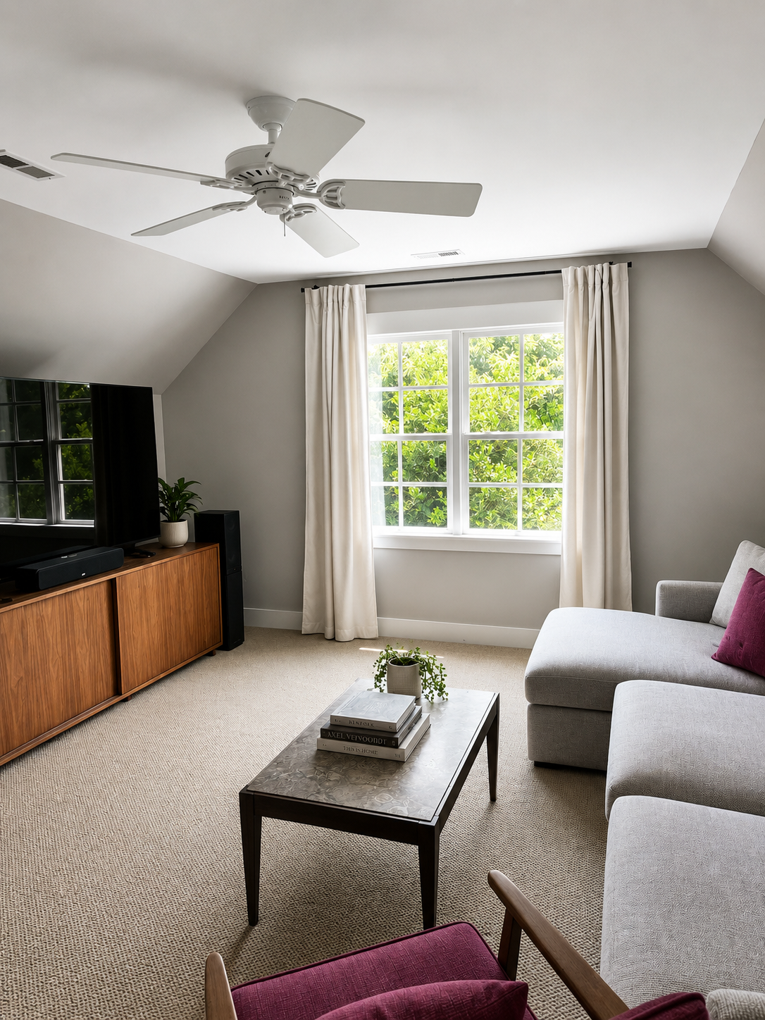 Upstairs entertainment room with vaulted ceiling, large TV, and walnut media console