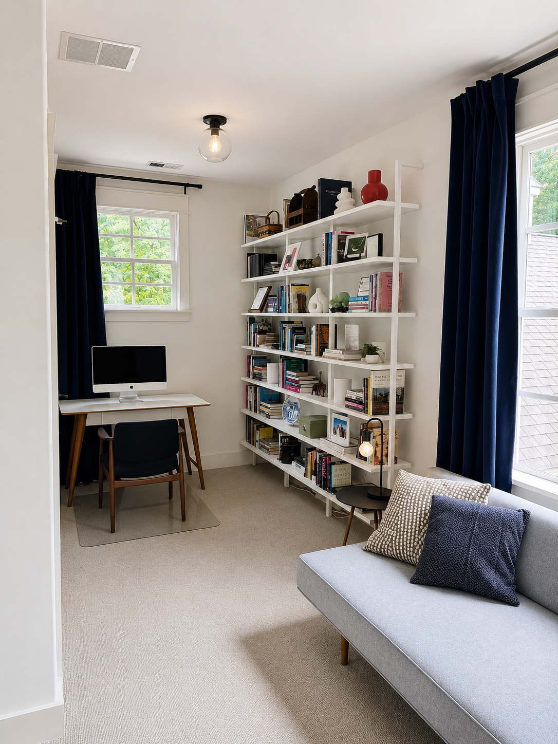 Second home office with writing desk, daybed, and library shelving